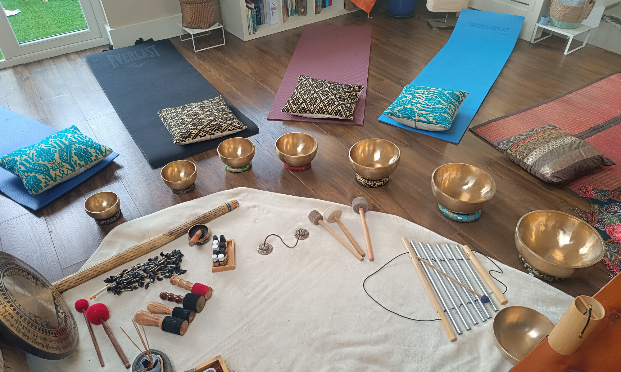 A room prepared for a sound healing group session, with himalayan bowls and other instruments.