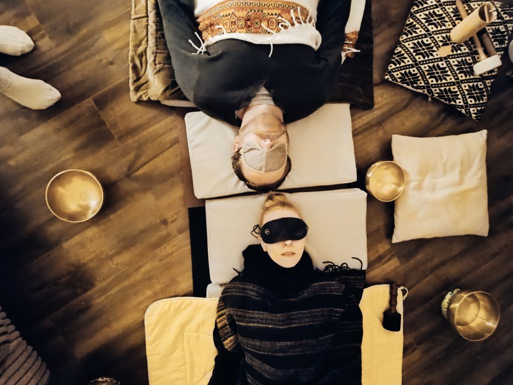 A couple laying down and receiving a sound healing session in harmony.